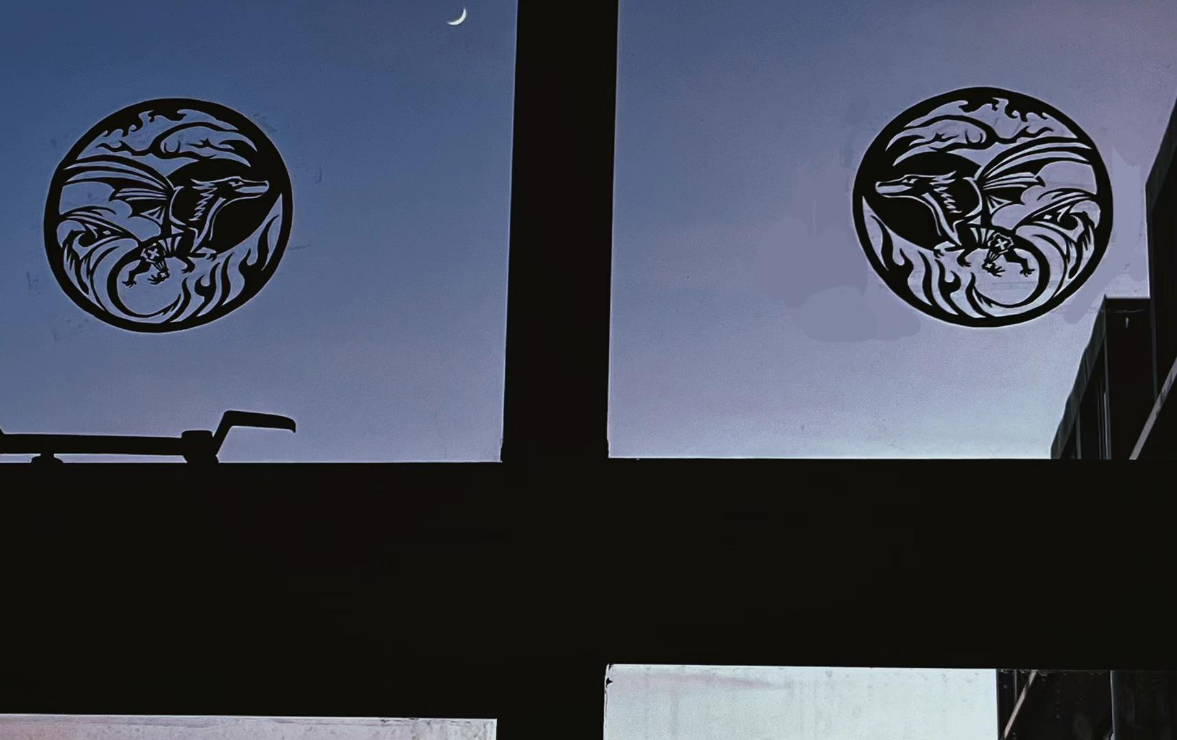 Two paper-cut dragons seen through a window at dusk